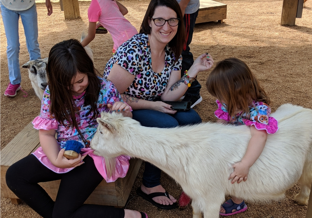 mom and kids petting a goat at the dallas zoo