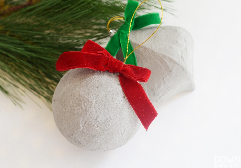 diy-concrete-christmas-ornaments-4-3 The finished concrete Christmas ornaments with red and green velvet bows.