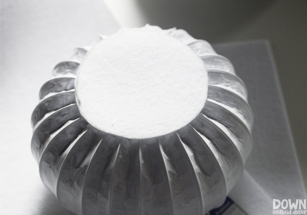 diy-dryer-vent-snowman-wide-4 A white felt circle being glued to the top of white dryer vent duct.