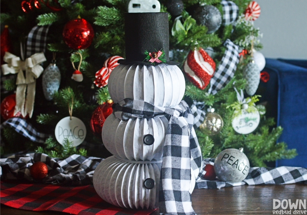 diy-dryer-vent-snowman-wide-8 The finished DIY Dryer Vent Snowman in front of a decorated Christmas tree.