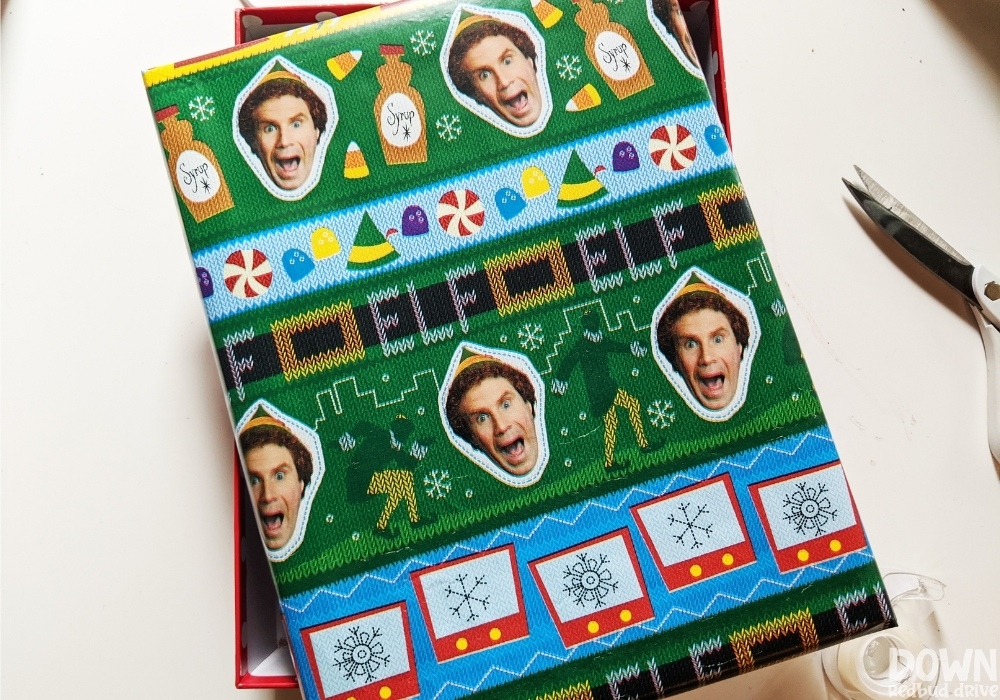 elf-food-groups-gift-idea-wide-3 Overhead picture of a gift box wrapped in elf wrapping paper.