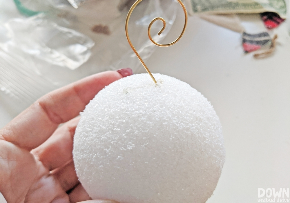 feather-ornament-diy-wide-2 Up close picture of a decorative ornament hook being glued onto a foam ball.