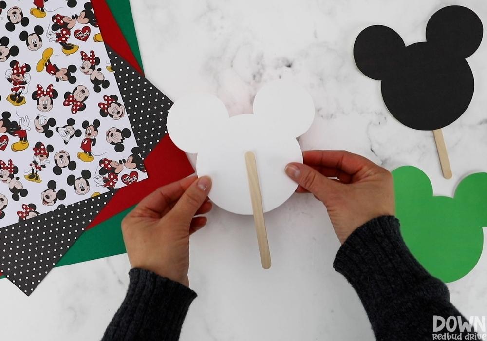 mickey-and-minnie-christmas-pops-wide-4-3 A popsicle stick hot glued to a mickey mouse head cutout.