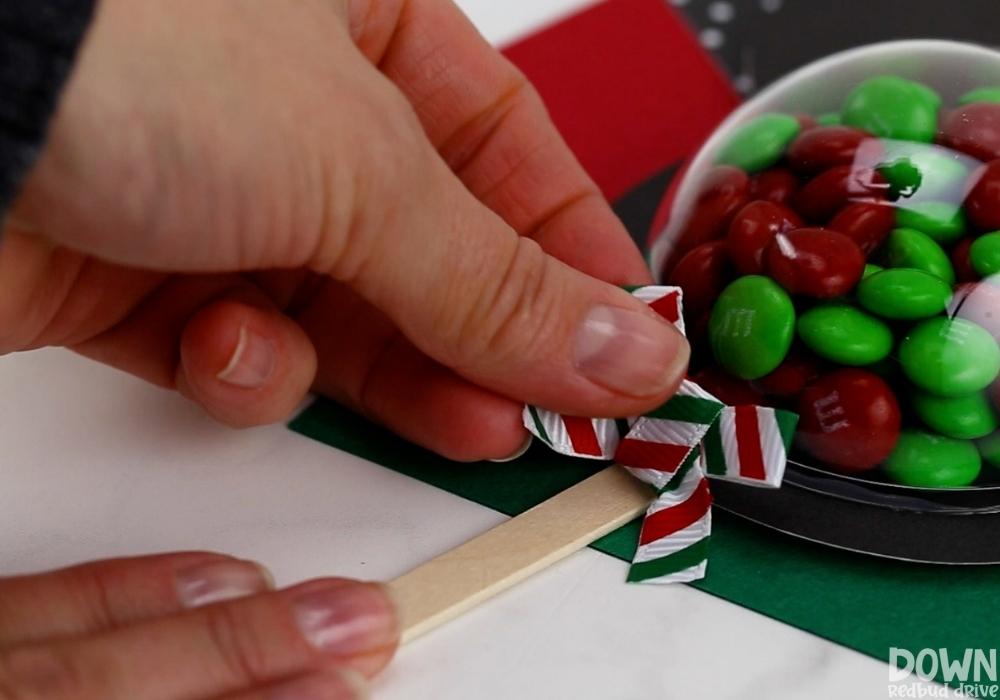 mickey-and-minnie-christmas-pops-wide-5 A Christmas bow being glued to an M&M pop.