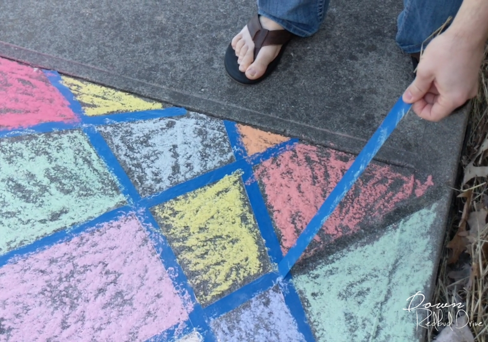 sidewalk-chalk-mosaic-5 pulling blue painter's tape off a sidewalk that's been colored with sidewalk chalk