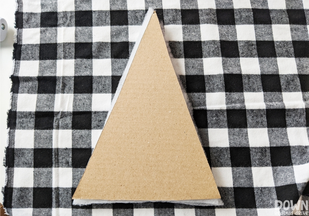 wood-and-fabric-christmas-tree-diy-wide-5 The triangular cardboard and quilt batting sitting on a piece of black and white buffalo check fabric.